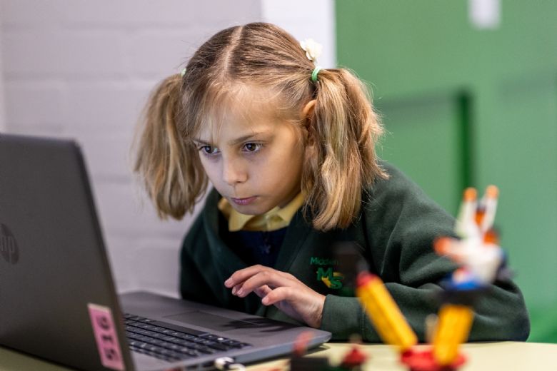 a white girl with pigtails looks at a laptop screen intently